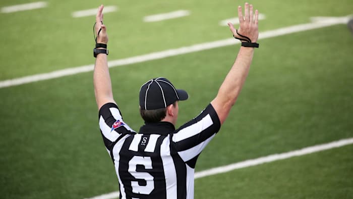 A college football ref signals for a touchdown